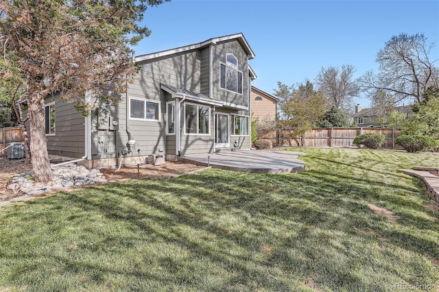 rear view of house featuring central air condition unit, a yard, and fence