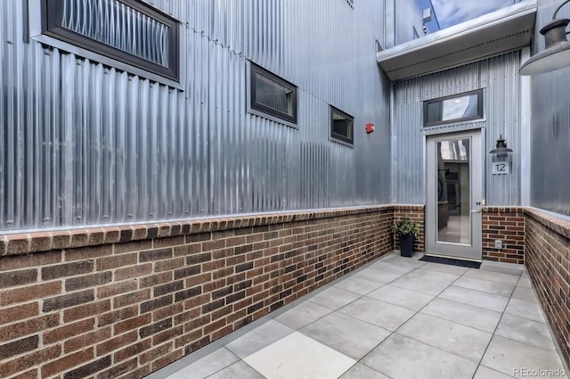 property entrance featuring brick siding and a patio