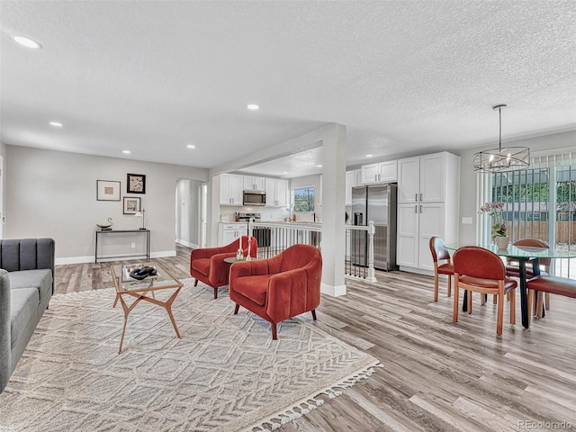 living room with a textured ceiling, light hardwood / wood-style flooring, and a notable chandelier