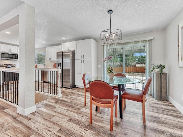 dining area featuring light wood-type flooring, a textured ceiling, and a chandelier