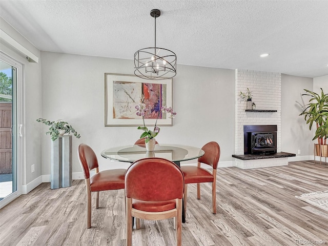 dining room with light hardwood / wood-style floors, a textured ceiling, and an inviting chandelier