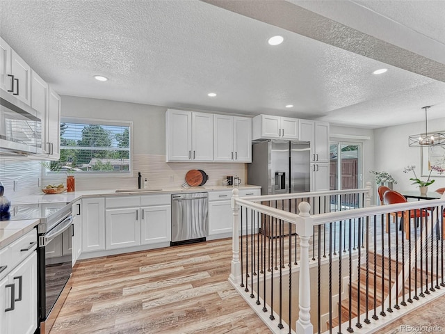 kitchen with backsplash, stainless steel appliances, white cabinetry, and sink