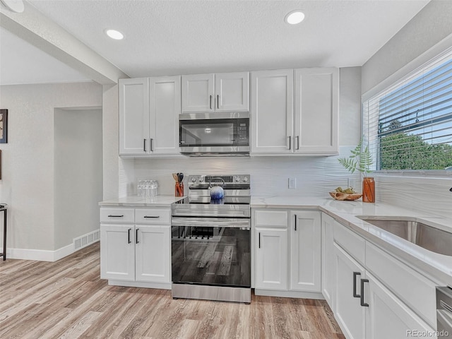 kitchen with backsplash, white cabinets, and stainless steel appliances