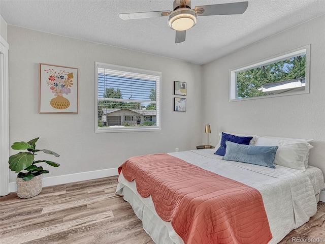 bedroom with ceiling fan, a textured ceiling, and light wood-type flooring