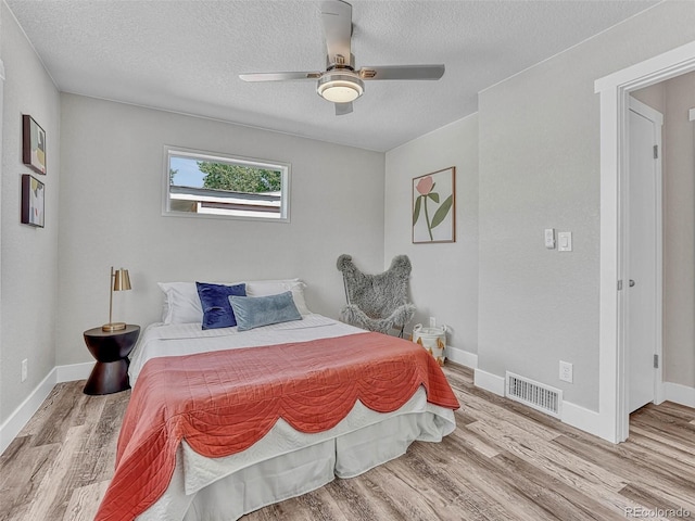 bedroom featuring ceiling fan, light hardwood / wood-style flooring, and a textured ceiling