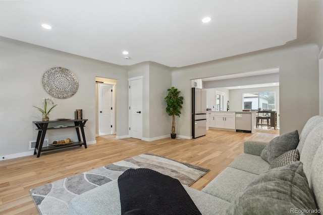 living room featuring sink and light hardwood / wood-style flooring