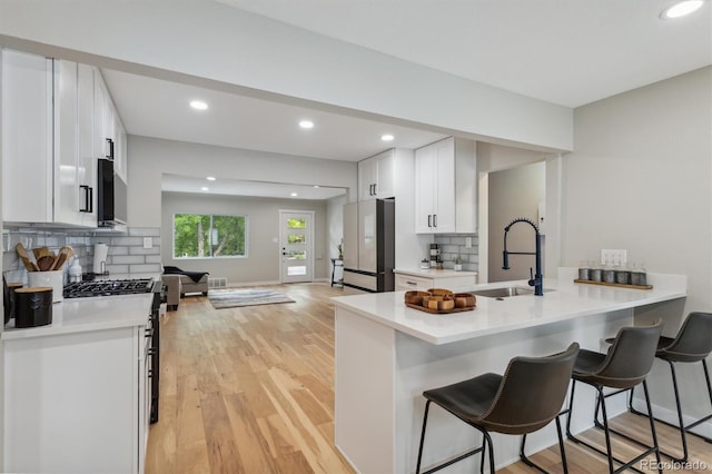 kitchen with light wood-type flooring, a breakfast bar, kitchen peninsula, and sink