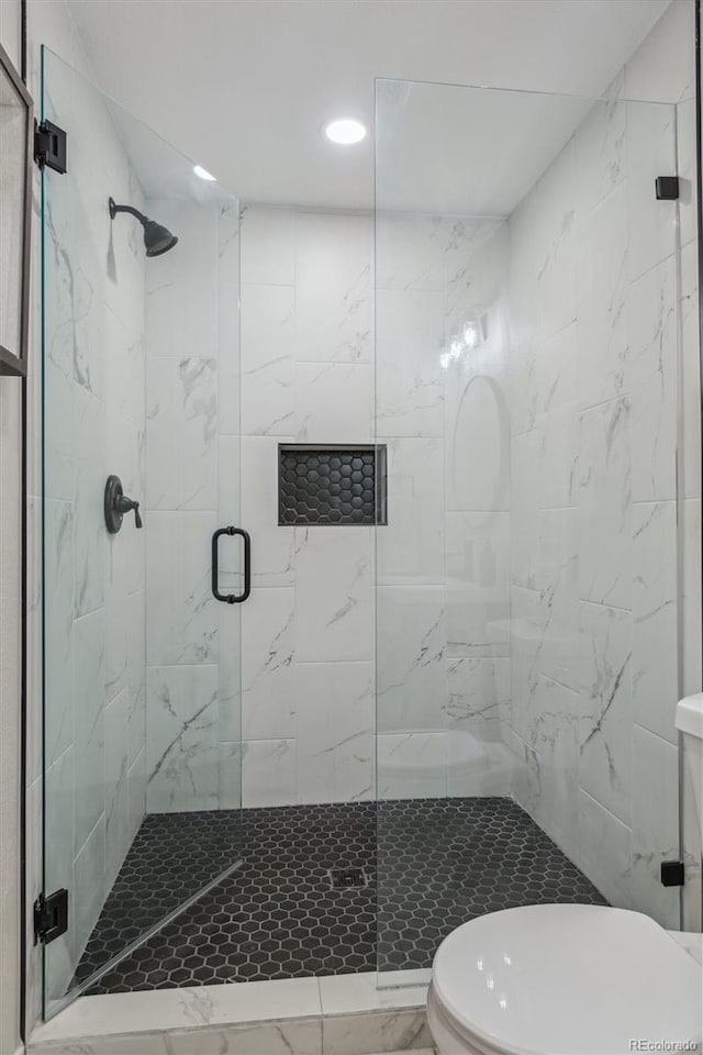 bathroom featuring a shower with shower door and toilet