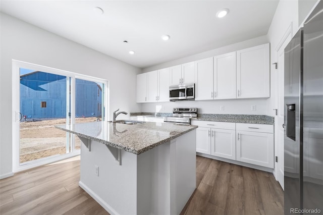 3889 N Shawee St, Aurora, CO 80019 - kitchen featuring stainless steel appliances, a sink, wood finished floors, white cabinets, and recessed lighting