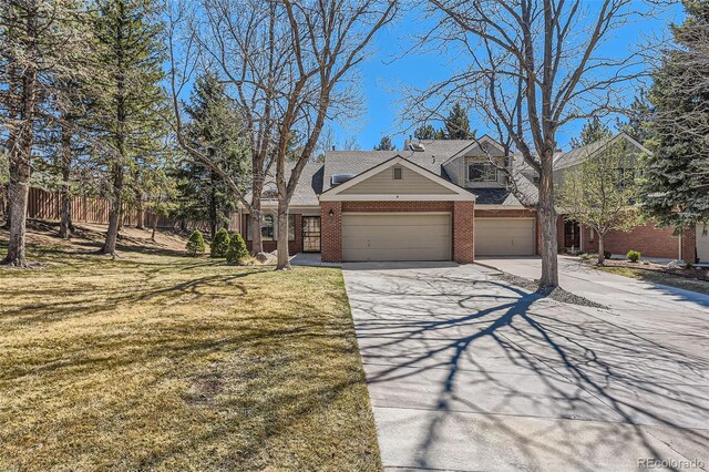 view of front of home with brick siding, a front yard, driveway, and a garage
