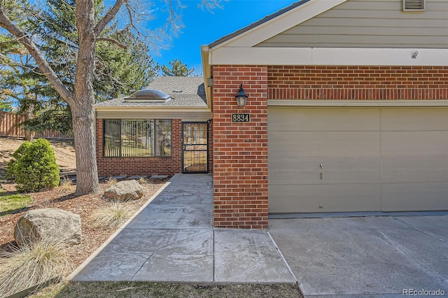 view of front of house featuring fence, an attached garage, and brick siding