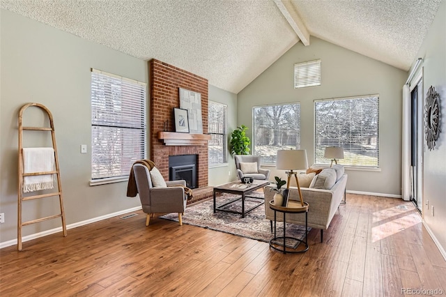 living area with hardwood / wood-style floors, a textured ceiling, baseboards, and a brick fireplace
