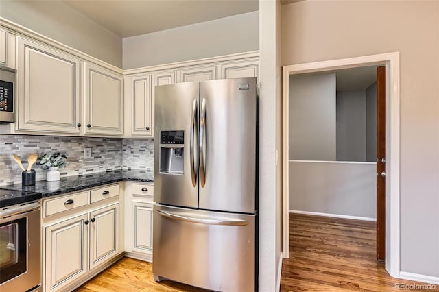 kitchen featuring light wood-type flooring, cream cabinets, appliances with stainless steel finishes, and decorative backsplash