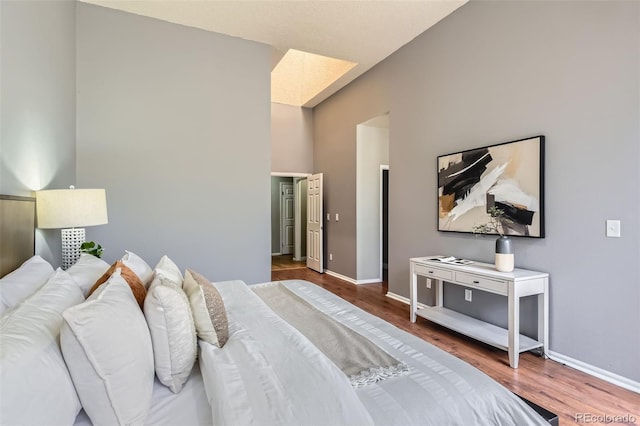 bedroom featuring a high ceiling, baseboards, and wood finished floors