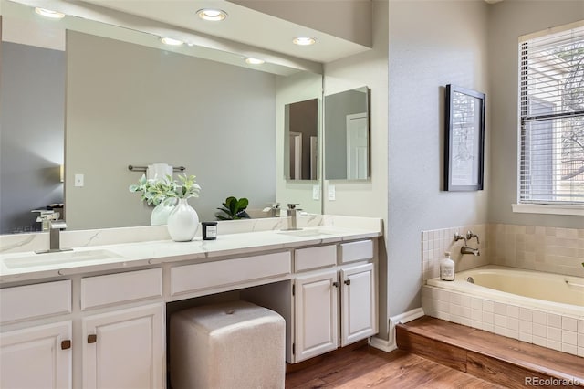 full bath with double vanity, wood finished floors, and a sink