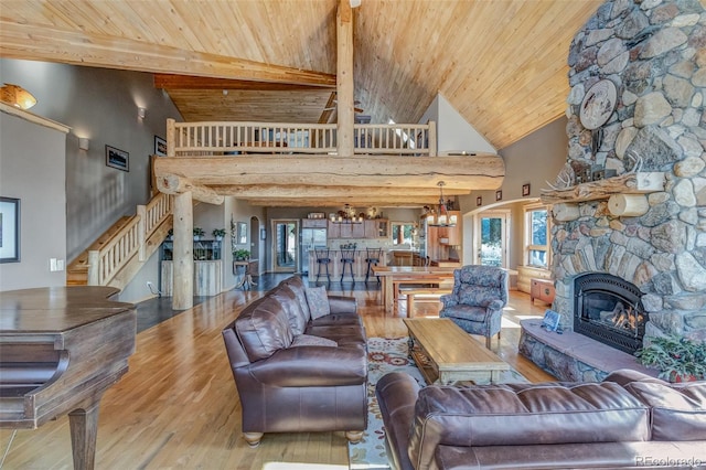 living room featuring a fireplace, light hardwood / wood-style floors, plenty of natural light, wooden ceiling, and an inviting chandelier