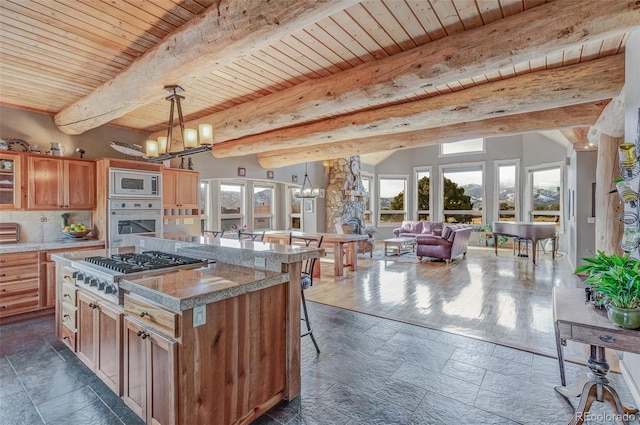 kitchen featuring appliances with stainless steel finishes, beam ceiling, a notable chandelier, a kitchen island, and decorative light fixtures