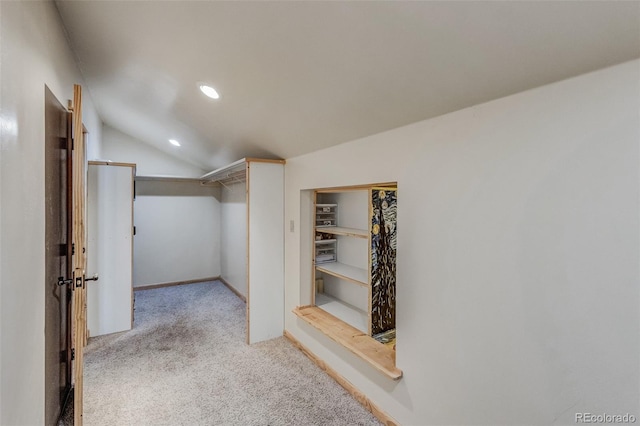 walk in closet with light colored carpet and vaulted ceiling