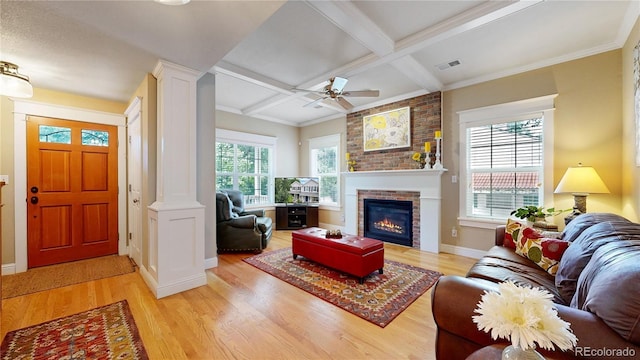 living room featuring beam ceiling, ceiling fan, coffered ceiling, a brick fireplace, and light hardwood / wood-style floors