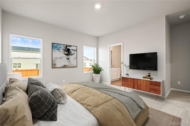 bedroom featuring carpet floors, multiple windows, and ensuite bath