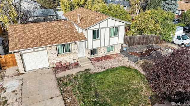 tudor home with a shingled roof, fence, driveway, and a garage