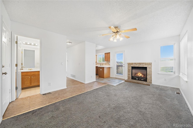 4064 S Himalaya Way, Aurora, CO 80013 - unfurnished living room featuring light colored carpet, a textured ceiling, ceiling fan, light tile patterned floors, and a brick fireplace