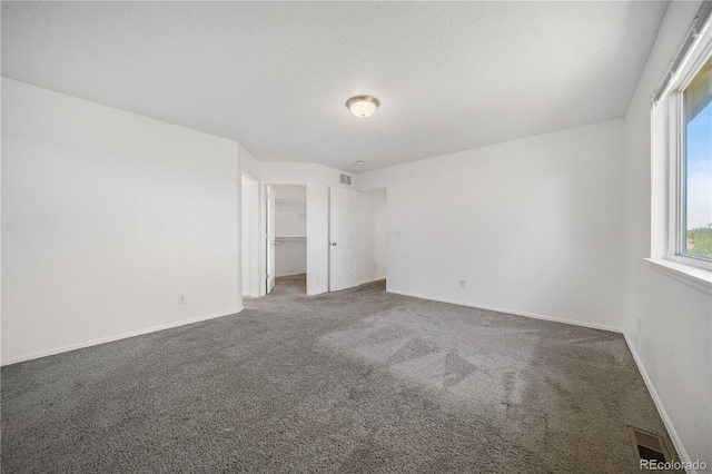 4064 S Himalaya Way, Aurora, CO 80013 - unfurnished bedroom featuring carpet, a walk in closet, and a textured ceiling