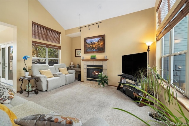 carpeted living room with baseboards, high vaulted ceiling, and a tile fireplace
