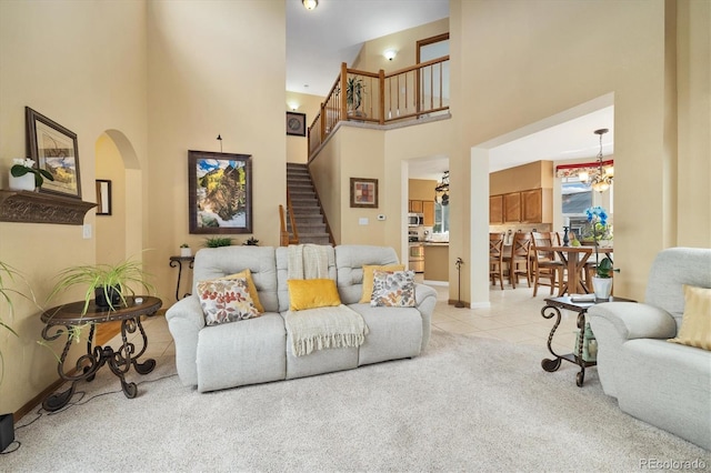 living area with baseboards, a high ceiling, stairway, arched walkways, and carpet