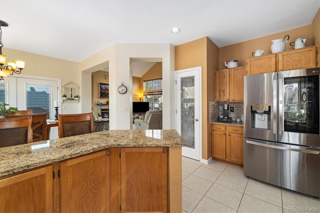 kitchen with light stone countertops, an inviting chandelier, light tile patterned floors, backsplash, and stainless steel refrigerator with ice dispenser