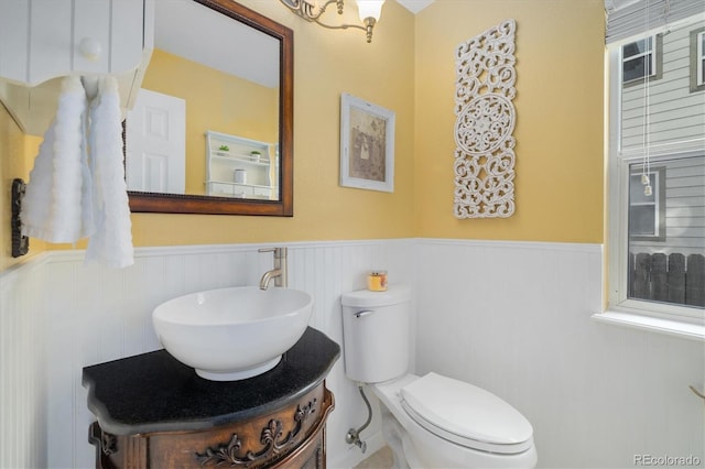 bathroom with toilet, wainscoting, and vanity