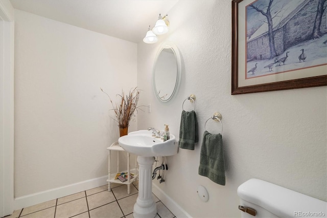 bathroom featuring toilet, baseboards, and tile patterned flooring