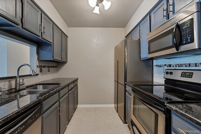 kitchen with appliances with stainless steel finishes, tasteful backsplash, dark stone counters, and light tile flooring