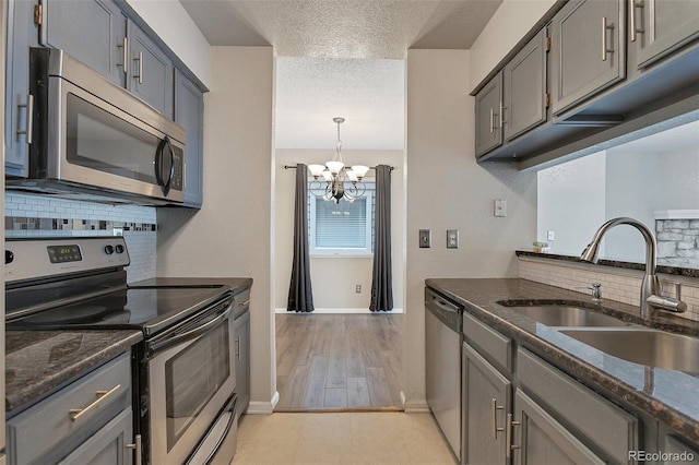 kitchen with stainless steel appliances, sink, light tile floors, tasteful backsplash, and a textured ceiling