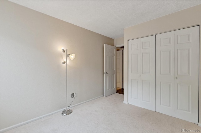 unfurnished bedroom with a closet, a textured ceiling, and light carpet