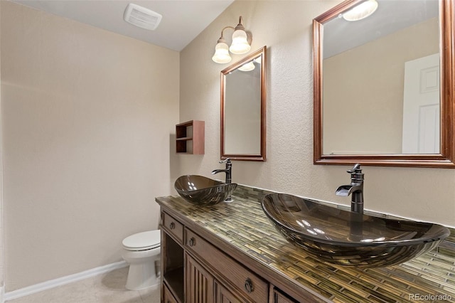 bathroom with toilet, tile floors, and vanity