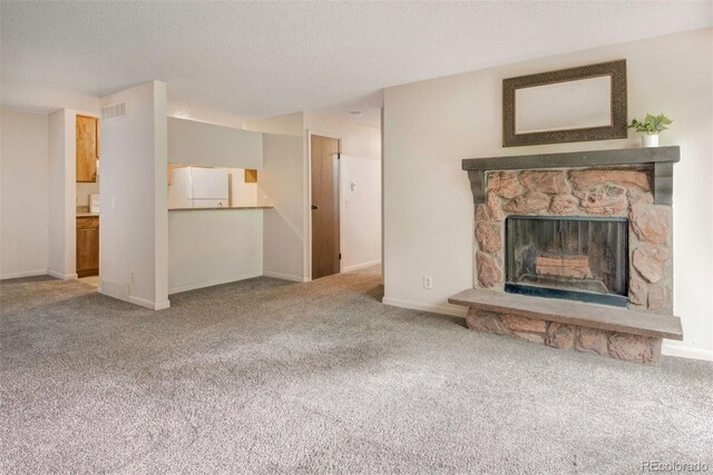 6505 Kalua Rd Unit 104B, Boulder, CO 80301 - unfurnished living room with carpet flooring, a textured ceiling, a stone fireplace, and baseboards