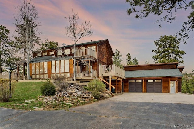 view of front of house with a balcony, stairs, and driveway
