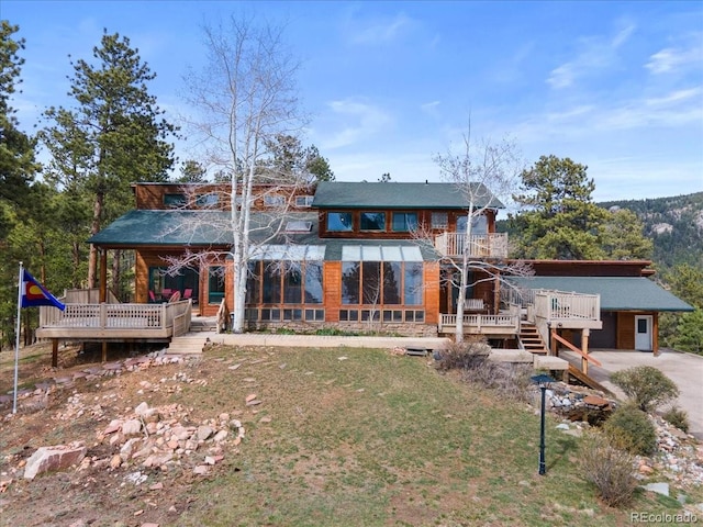 rear view of property with a wooden deck and driveway
