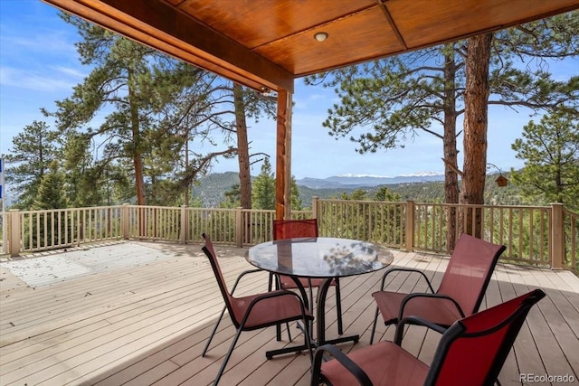 wooden terrace with outdoor dining area and a mountain view