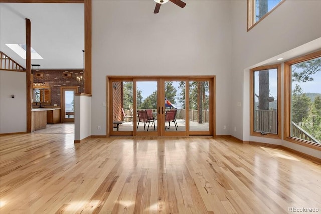 unfurnished living room with a healthy amount of sunlight, a high ceiling, and light wood-type flooring