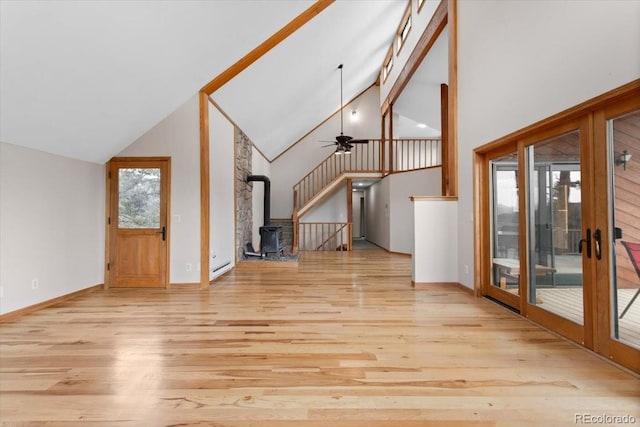 unfurnished living room featuring high vaulted ceiling, a wood stove, ceiling fan, and wood finished floors