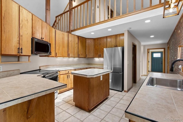 kitchen with stainless steel appliances, light tile patterned flooring, a sink, and a towering ceiling