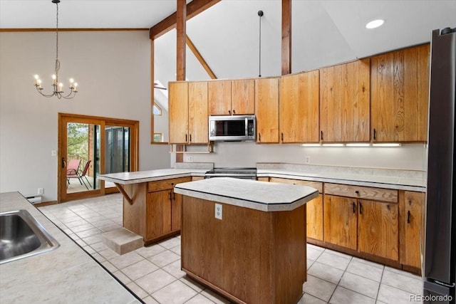 kitchen featuring high vaulted ceiling, stainless steel appliances, a notable chandelier, light countertops, and a kitchen island