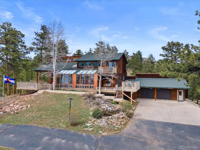 view of front of property with covered porch, a garage, concrete driveway, a front yard, and a balcony