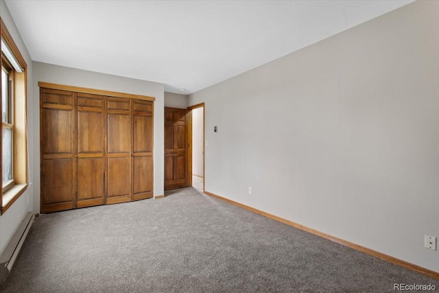 unfurnished bedroom with baseboards, baseboard heating, a closet, and light colored carpet