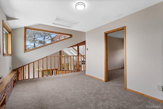 empty room featuring lofted ceiling, carpet floors, and baseboards