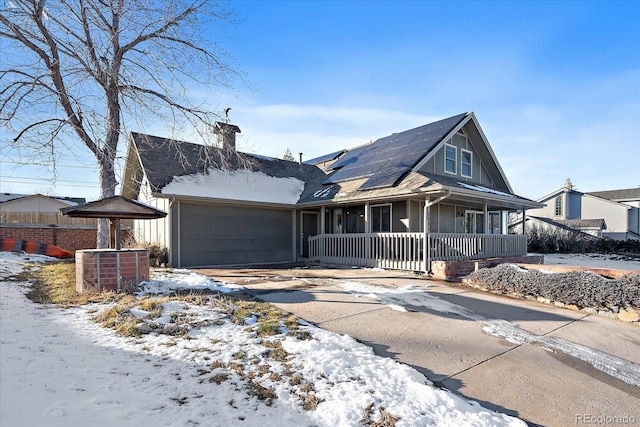 view of front of home featuring solar panels, a porch, and a garage