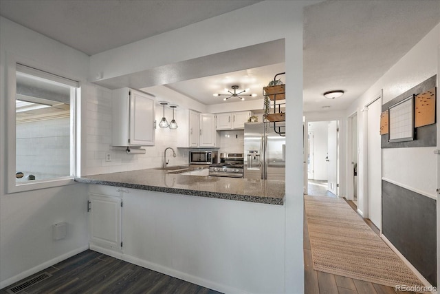 kitchen with white cabinets, sink, dark hardwood / wood-style floors, kitchen peninsula, and stainless steel appliances