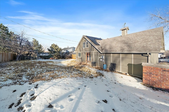 snow covered rear of property featuring central AC unit